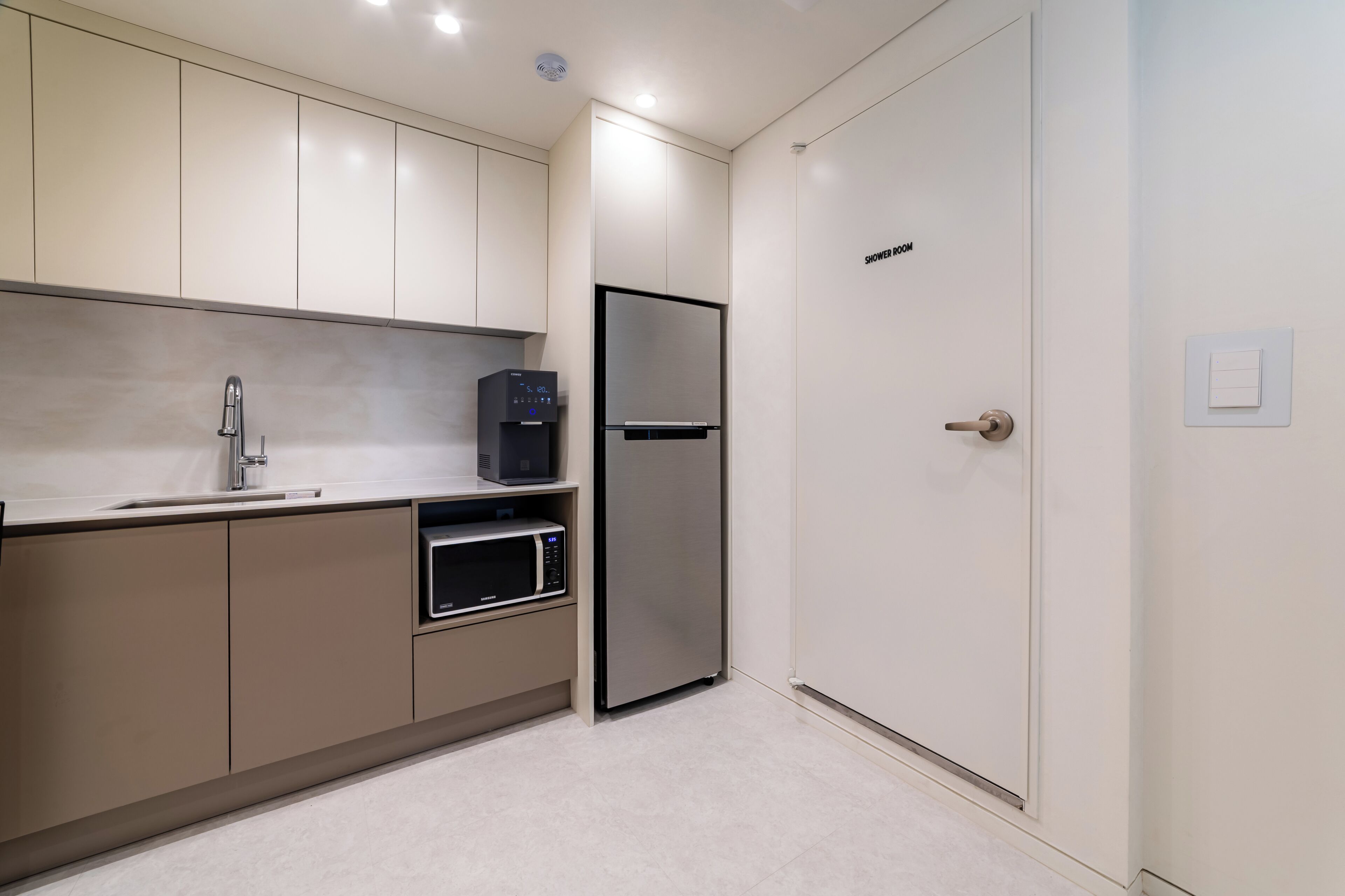 Una cocina moderna con microondas integrado, refrigerador de acero inoxidable y dispensador de agua.
