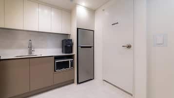 Una cocina moderna con microondas integrado, refrigerador de acero inoxidable y dispensador de agua.