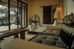 A bedroom with a bed, a hanging lamp, and a view of trees through large windows. - La Pausa Hotelbistro (San Luis)