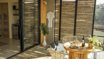 Un espacio moderno para comer al aire libre con muebles de mimbre, una mesa dispuesta para dos personas y vistas del paisaje circundante.