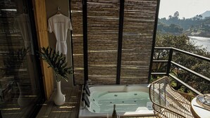A balcony with a hot tub, a table with glasses and a bottle, and a wicker chair. - La Pausa Hotelbistro (San Luis)