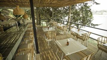 Un área de comedor al aire libre con mobiliario de mimbre y vistas al agua.