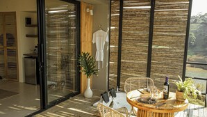 A modern outdoor dining area with wicker furniture, a table set for two, and a view of the surrounding landscape. - La Pausa Hotelbistro (San Luis)