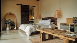 A bedroom with a bed, bedside table, and a wooden bench. - La Pausa Hotelbistro (San Luis)