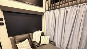 Habitació moderna amb un sofà marró fosc, una taula de fusta i un ventilador de sostre.