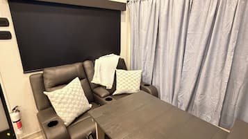Una habitación moderna con un sofá marrón oscuro, una mesa de madera y un ventilador de techo.
