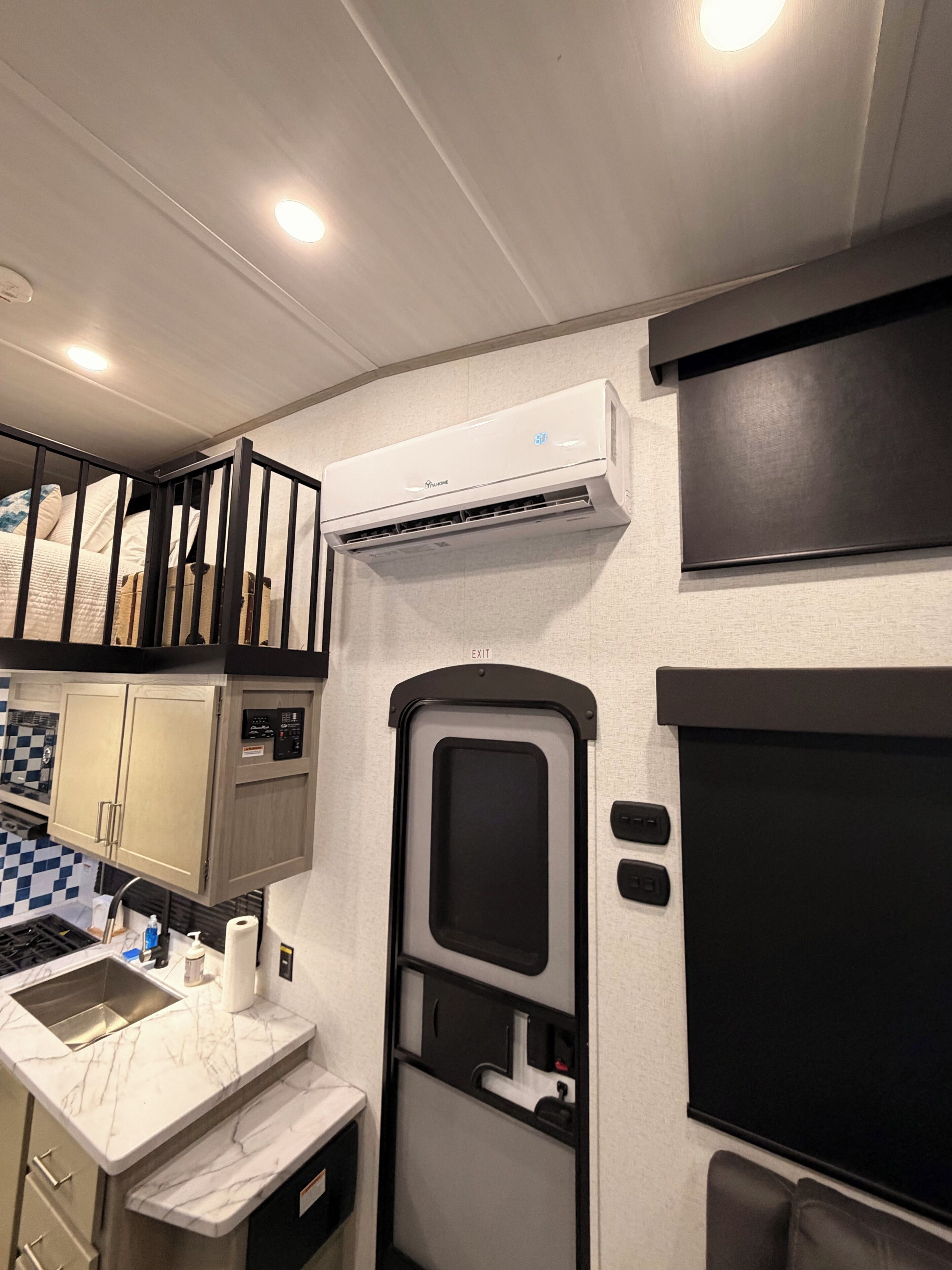 A compact kitchen with a sink, cabinets, and an air conditioning unit.
