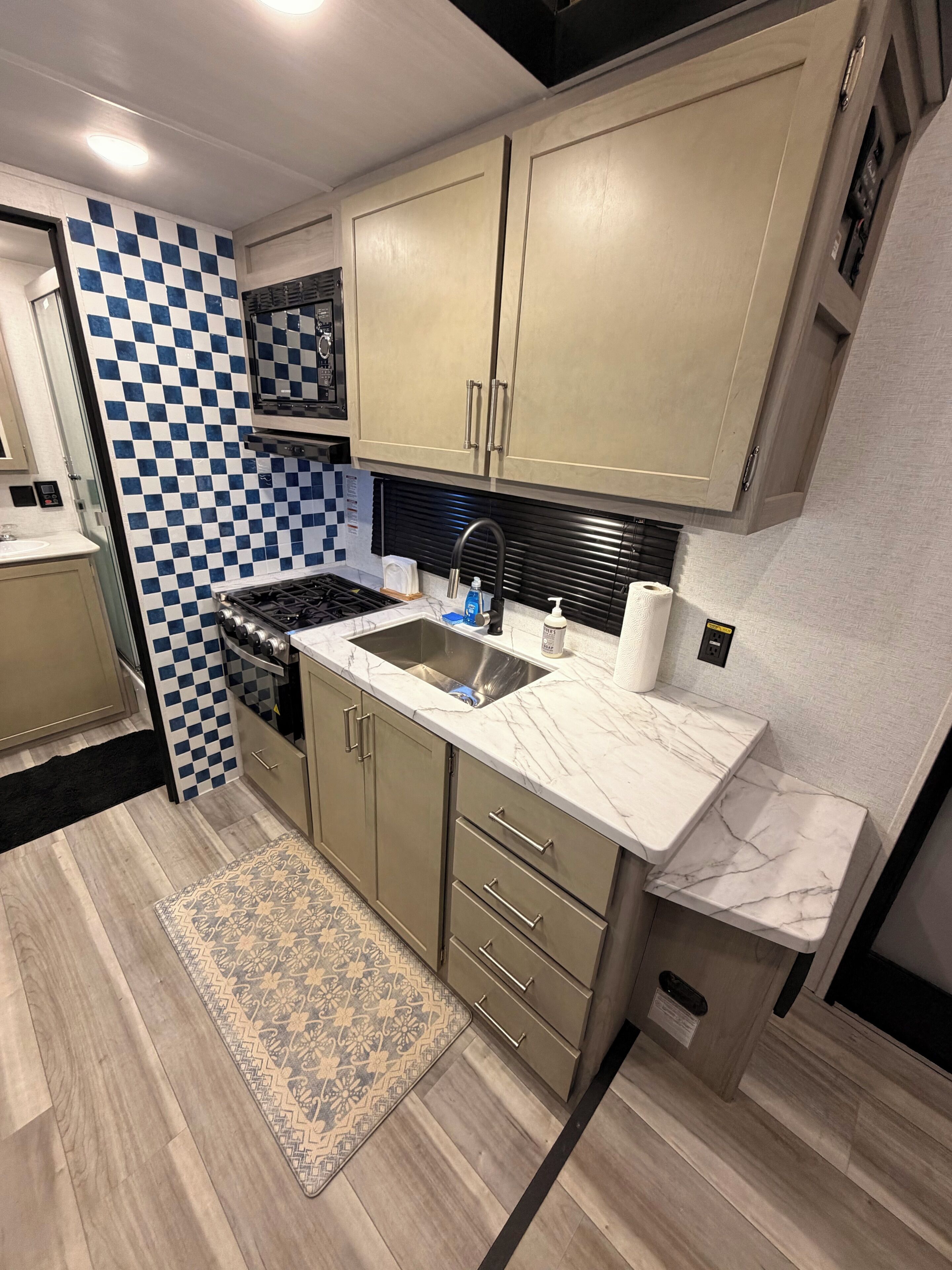 Una cocina compacta con salpicadero a cuadros, estufa, lavabo y microondas.