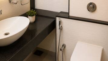 Un baño moderno con un lavamanos blanco, un inodoro y una ducha.