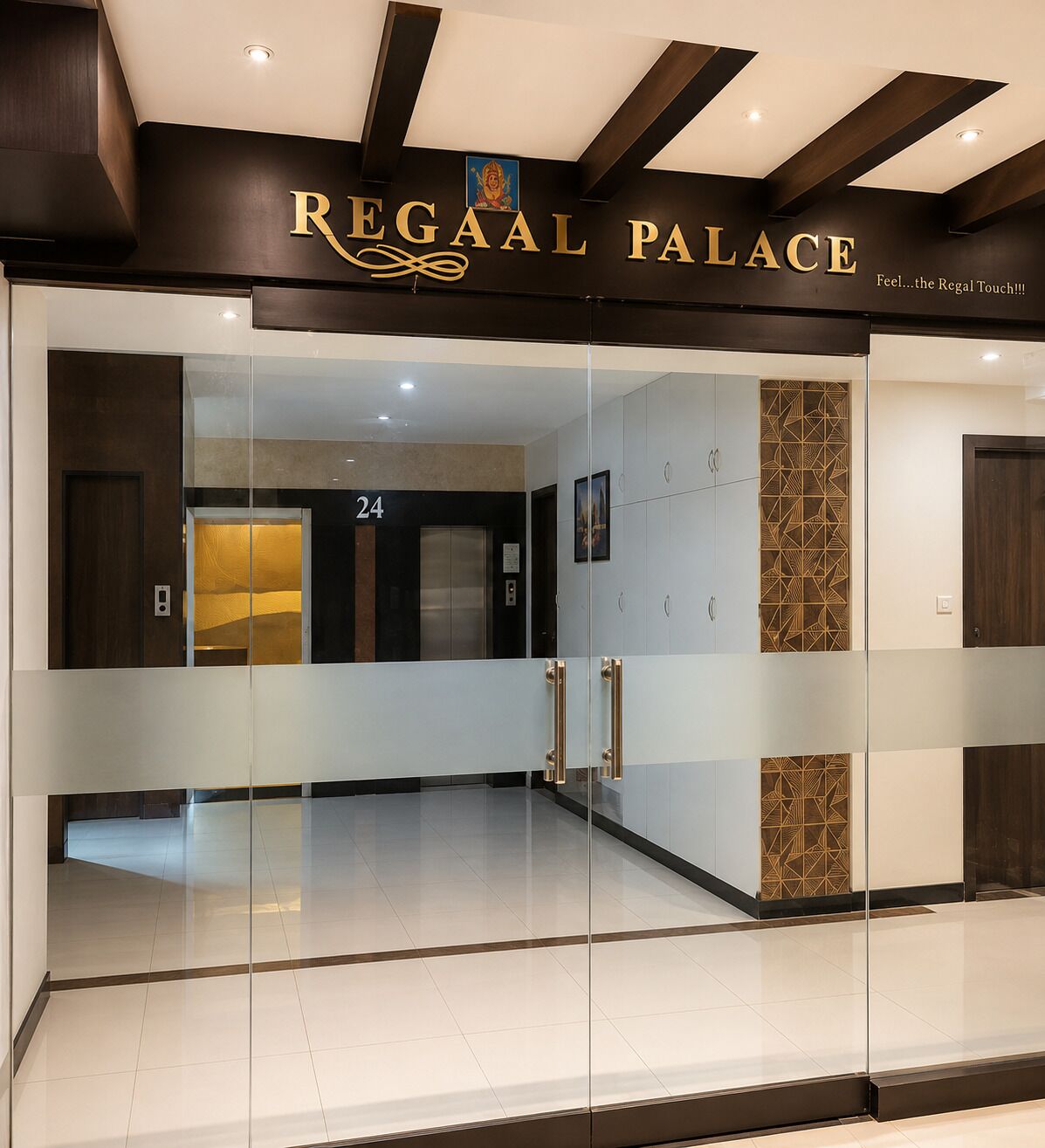 L’entrée du palais Regaal est marquée par une porte en verre, une enseigne au-dessus indiquant « Palais Regaal », et le numéro « 24 » est visible à l’intérieur.