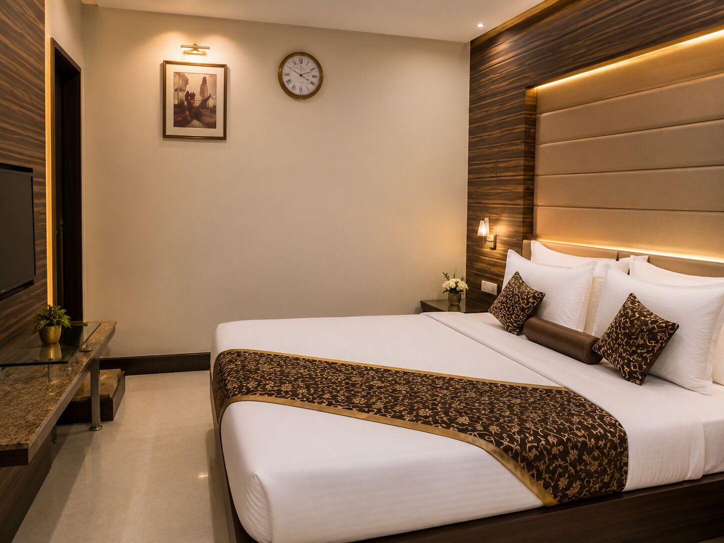 Habitación de hotel con una cama grande, una mesita de noche, un reloj y un cuadro en la pared.