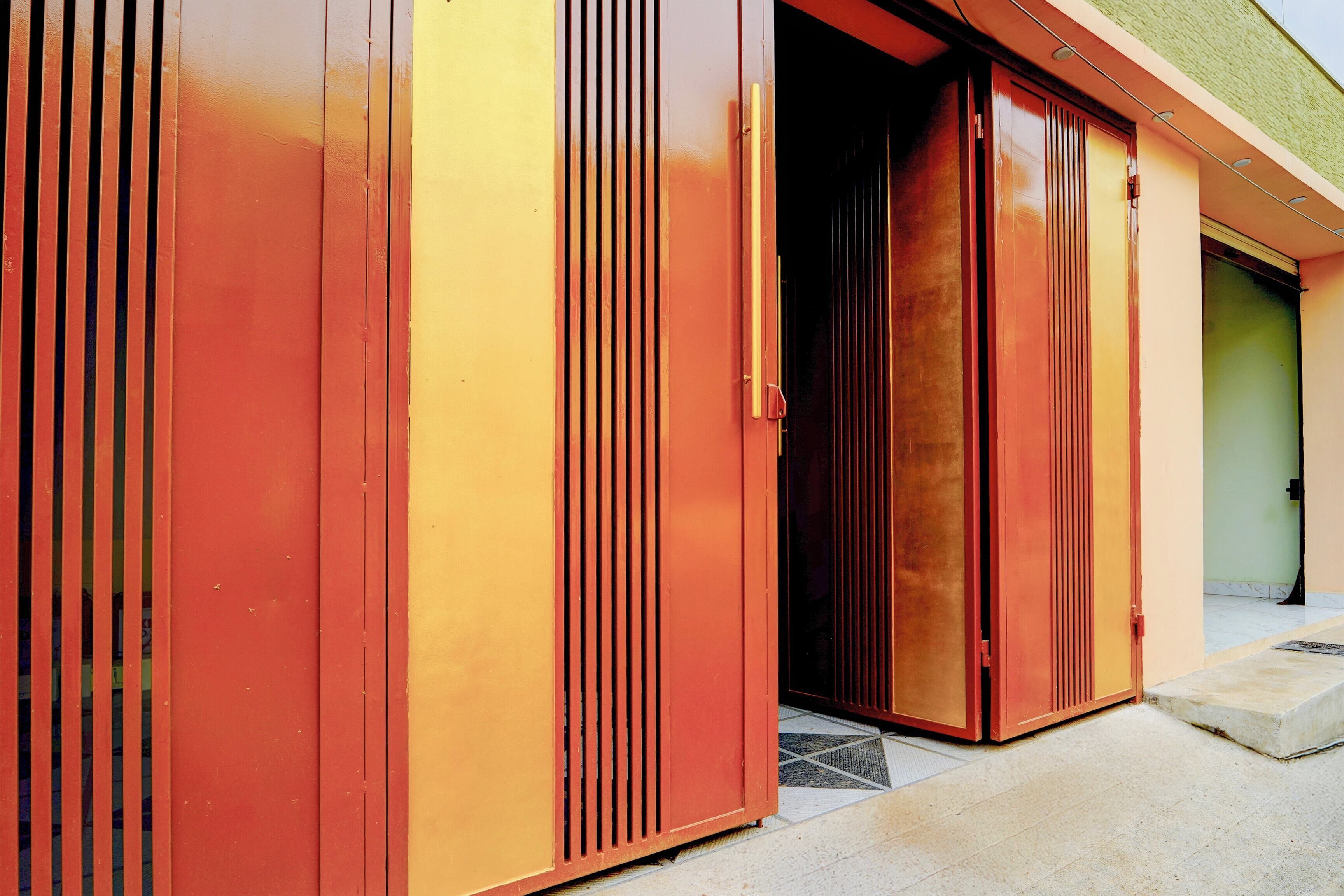 A building with a series of red and yellow doors, some of which are open, revealing a dark interior.