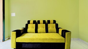 A yellow sofa with black accents in a room with green walls. - Collection O Thanjavur New Bus Terminal (Thanjavur)