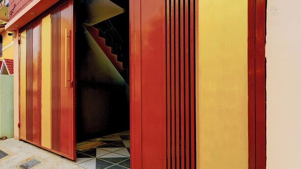 A staircase leading to a dark interior, with a red and yellow exterior wall. - Collection O Thanjavur New Bus Terminal (Thanjavur)