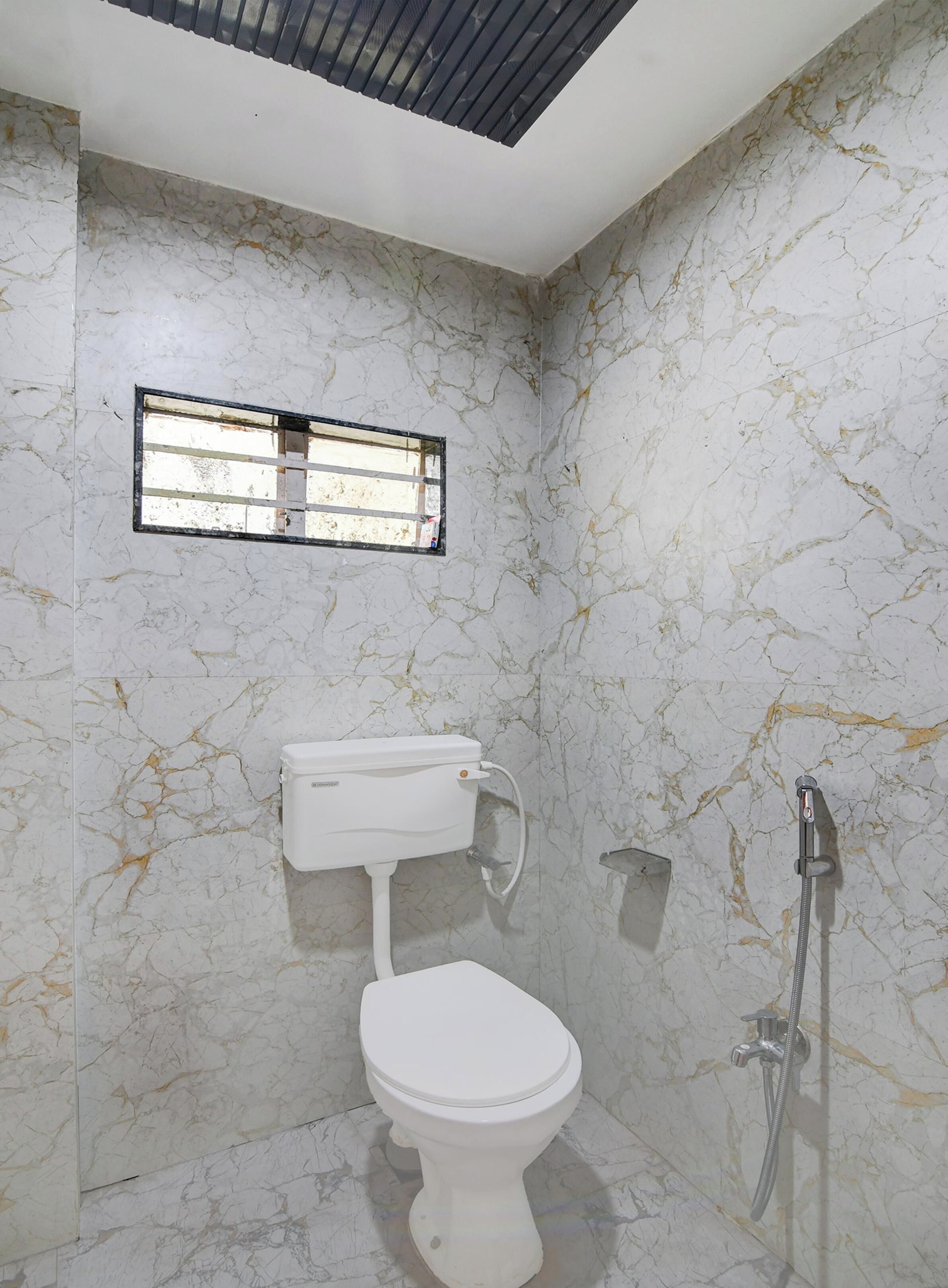 A bathroom with a toilet, a shower, and a window.