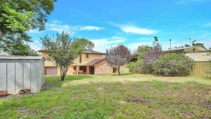 A residential property with a fenced yard, a detached garage, and a house with a sloped roof.