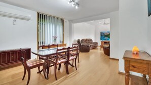 A spacious living area with a dining table, chairs, a sofa, and a TV.