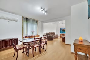A spacious living area with a dining table, chairs, a sofa, and a TV.