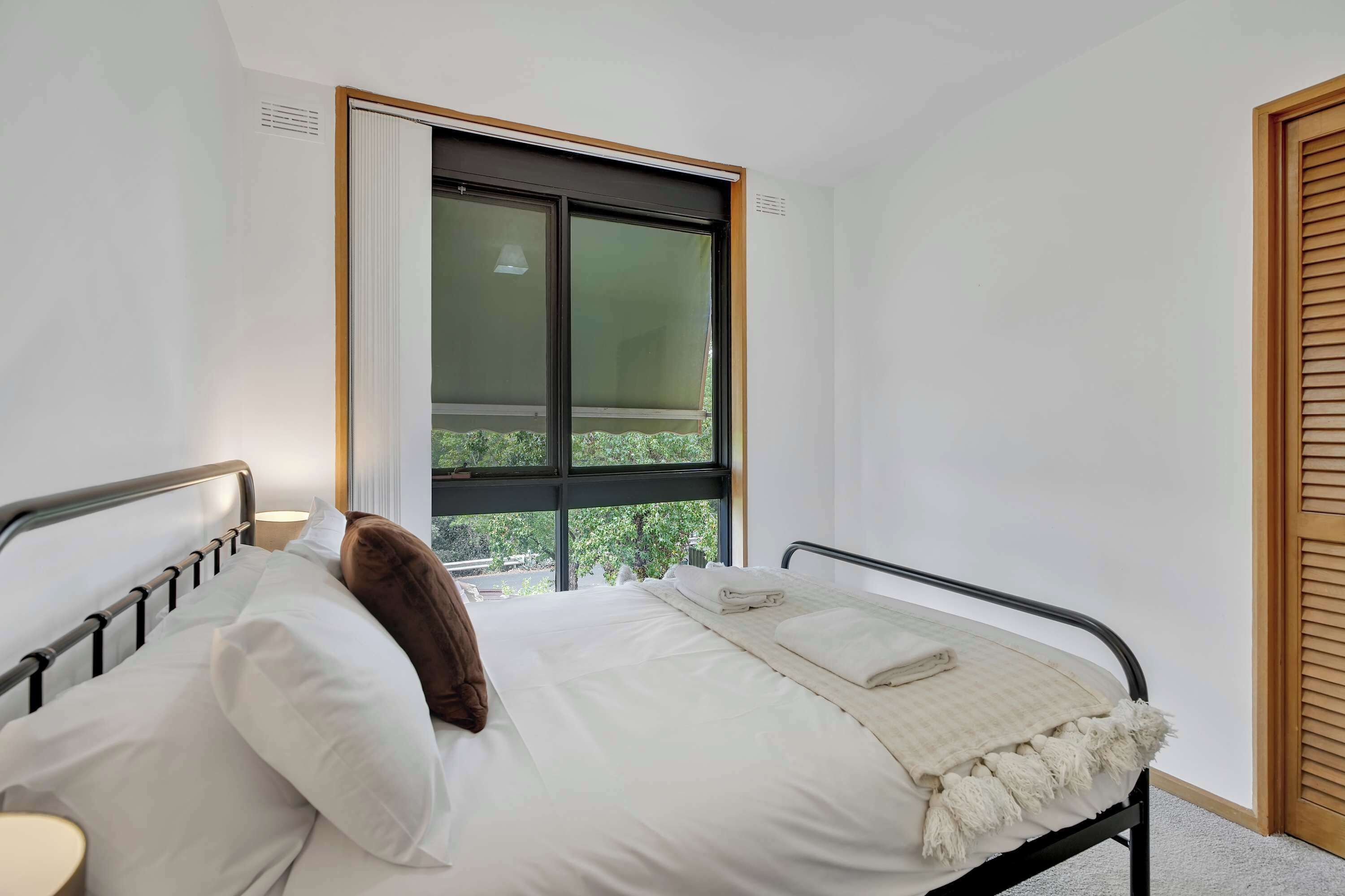 A bedroom with a bed, a window, and a door.