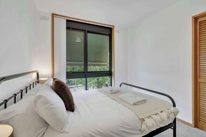 A bedroom with a bed, a window, and a door.