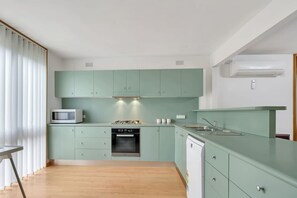 A compact kitchen with teal cabinets, a microwave, a stove, and a dishwasher.