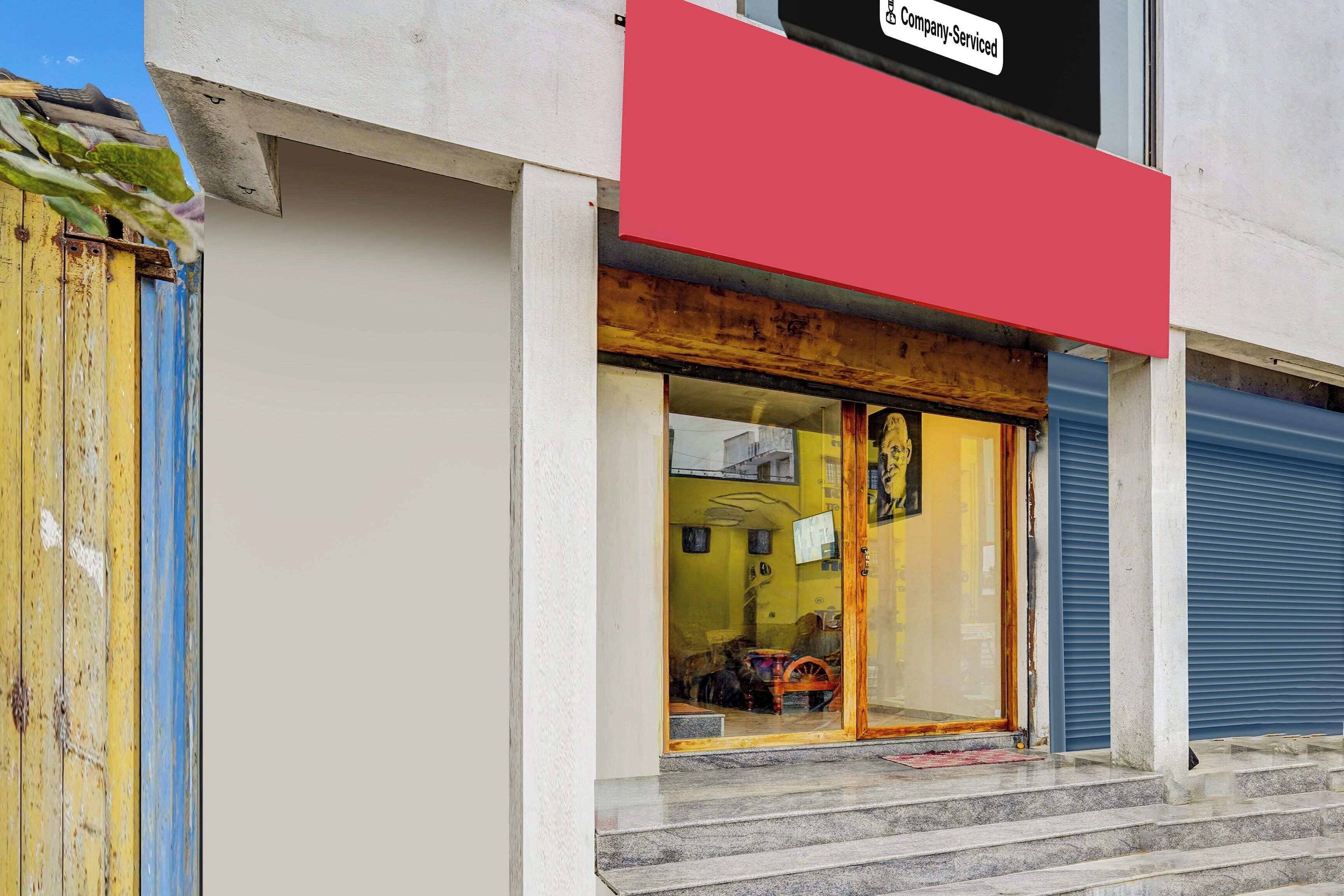 A building with a red sign above the entrance, a glass door, and a blue shutter door.