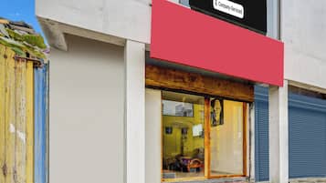 A building with a red sign above the entrance, a glass door, and a blue shutter door.