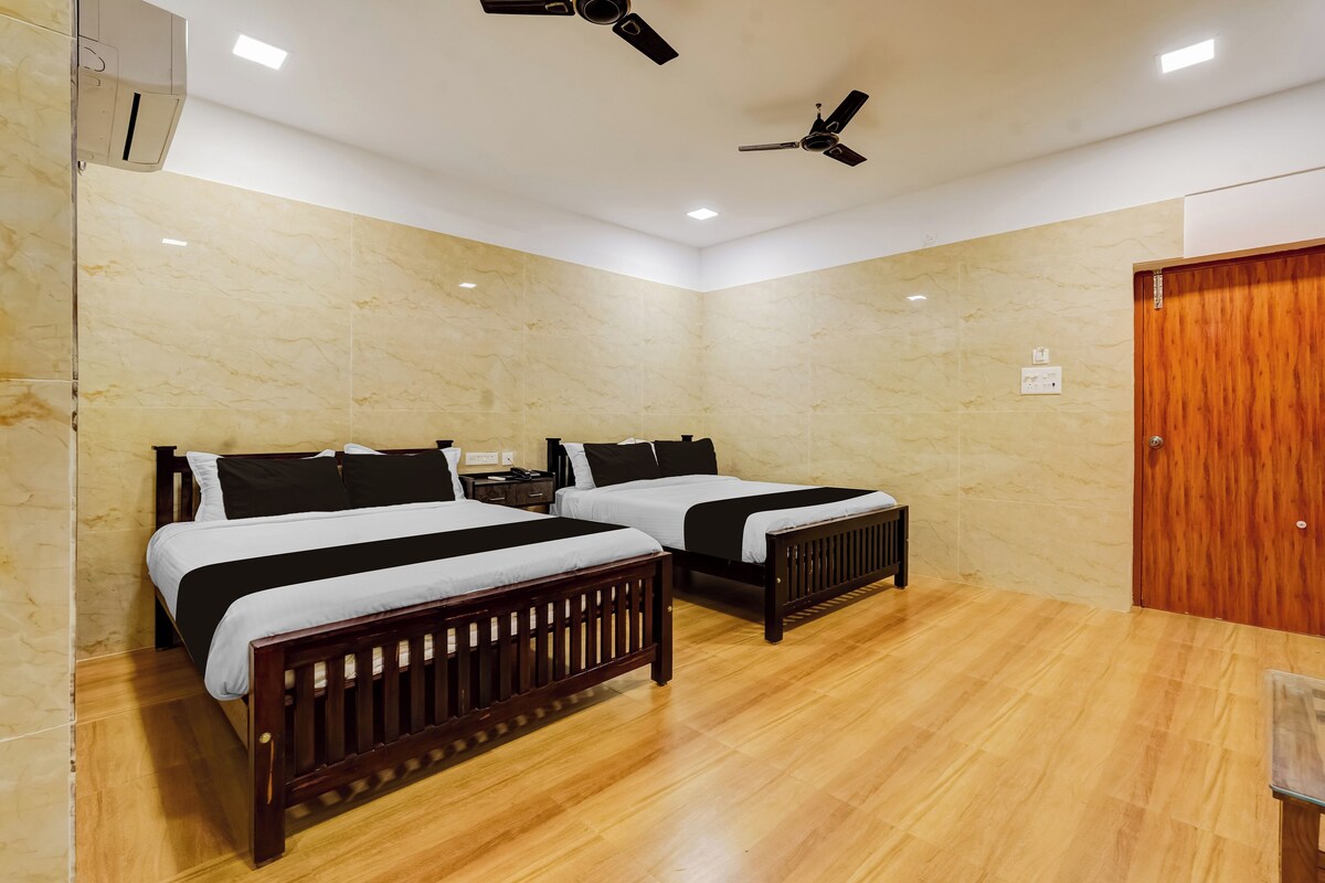 Una habitación de hotel con dos camas, piso de madera, paredes de mármol, ventiladores de techo y una puerta de madera.