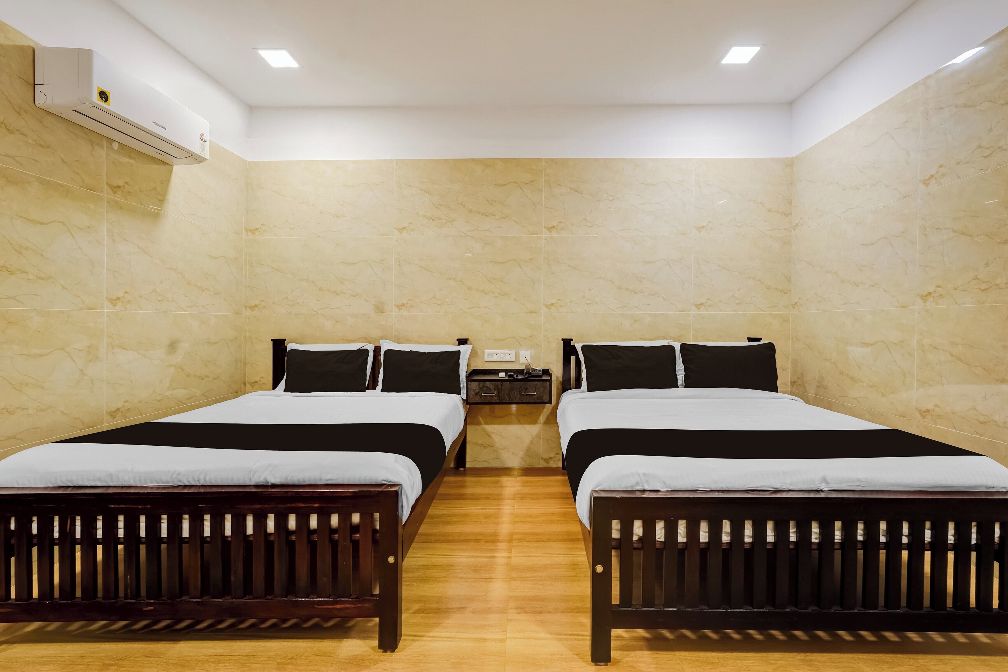 A hotel room with two beds, a nightstand, and an air conditioning unit.
