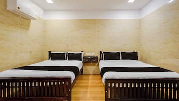 A hotel room with two beds, a nightstand, and an air conditioning unit.