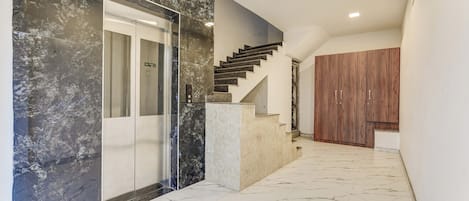 Un couloir doté d’un sol en marbre, d’un escalier en bois et d’une armoire en bois.