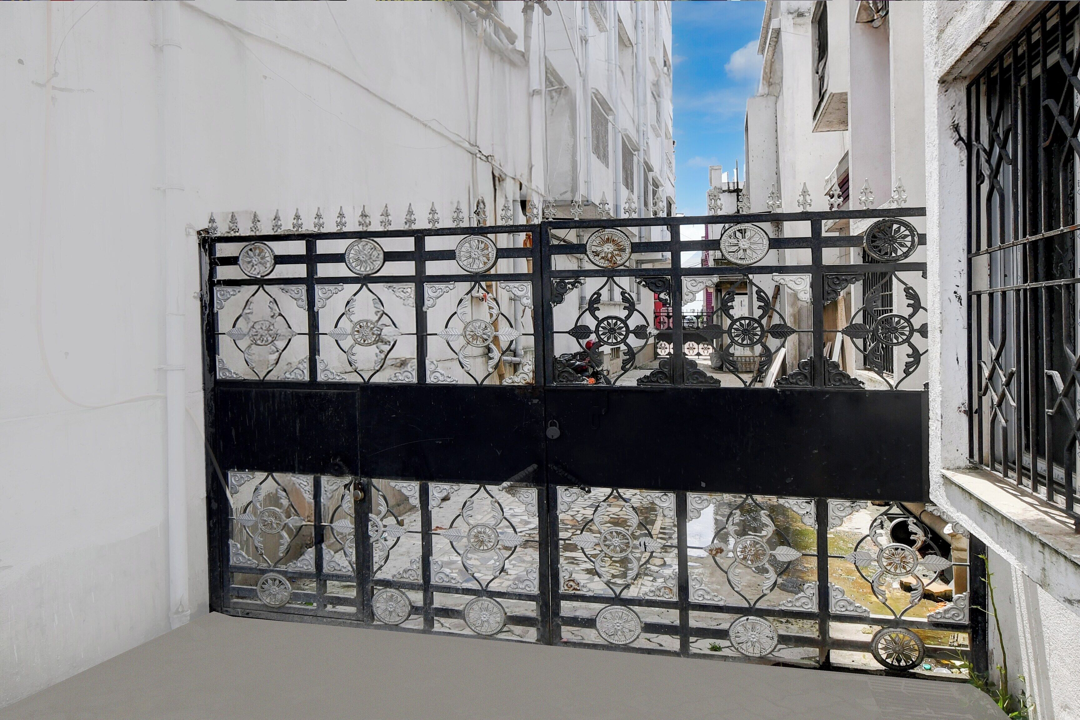 A gated entrance with decorative metalwork and a clear view of the street beyond.