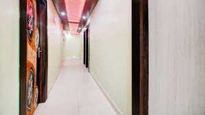 A corridor with a tiled floor, a wooden door with a decorative panel, and a ceiling with recessed lighting. - Collection O Tarapith Railway Junction (Tarapith)