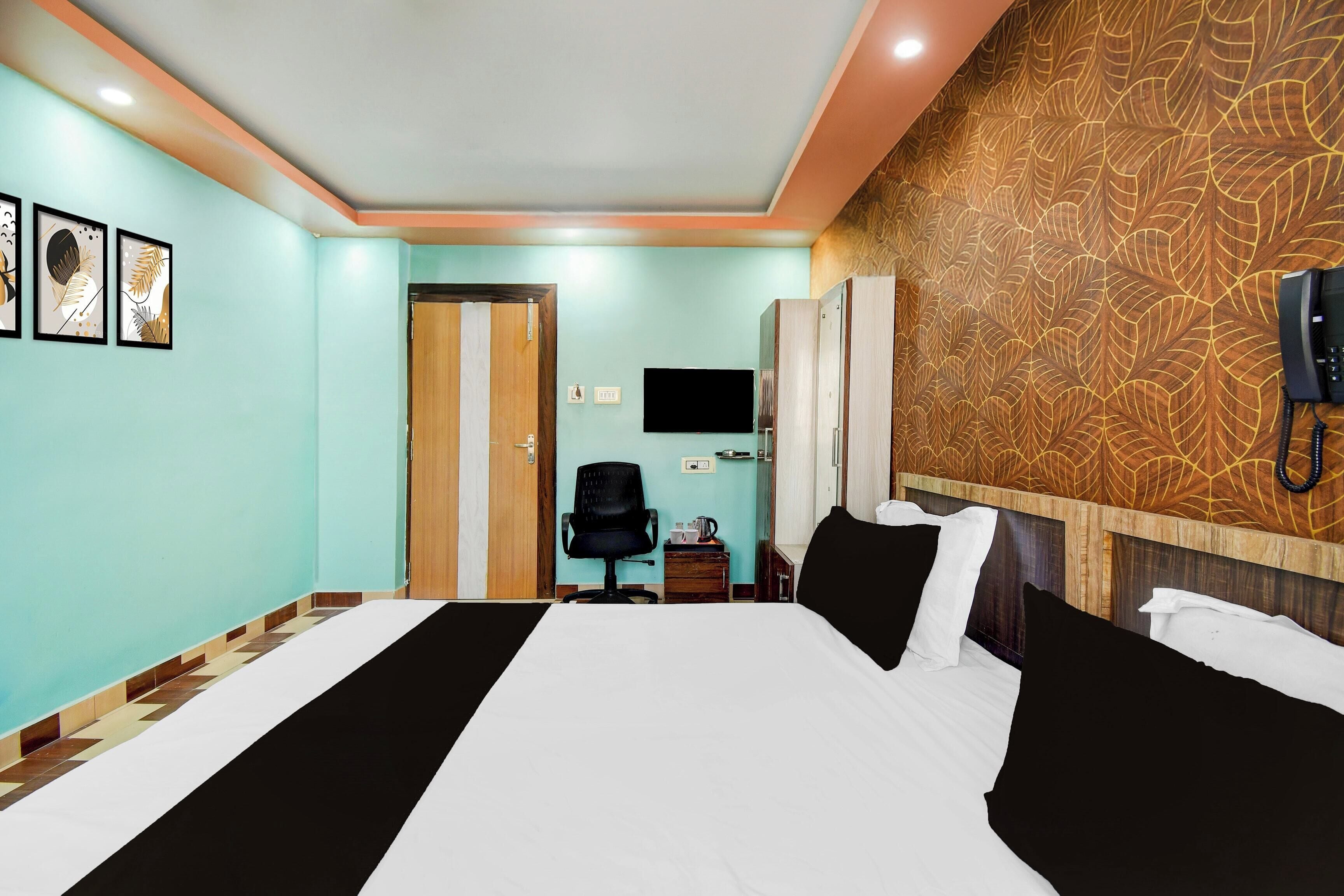 A hotel room with a bed, a desk, a chair, a TV, and a telephone.