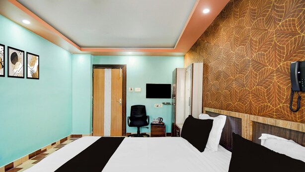 A hotel room with a bed, a desk, a chair, a TV, and a telephone. - Collection O Tarapith Railway Junction (Tarapith)