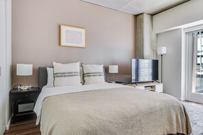 Un dormitorio moderno con una cama, dos mesitas de noche, un televisor y un cuadro enmarcado en la pared.