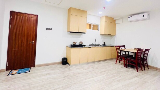 Cocina compacta con comedor, muebles de madera, encimera negra y ventilador de techo.