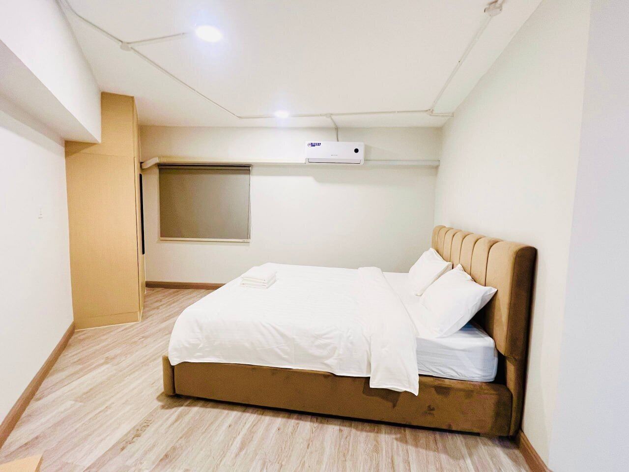 A bedroom with a bed, a window, and an air conditioning unit.