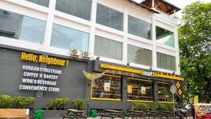 Un edificio con un letrero que anuncia comida callejera coreana, café y pastelería, vinos y bebidas, y una tienda de conveniencia.