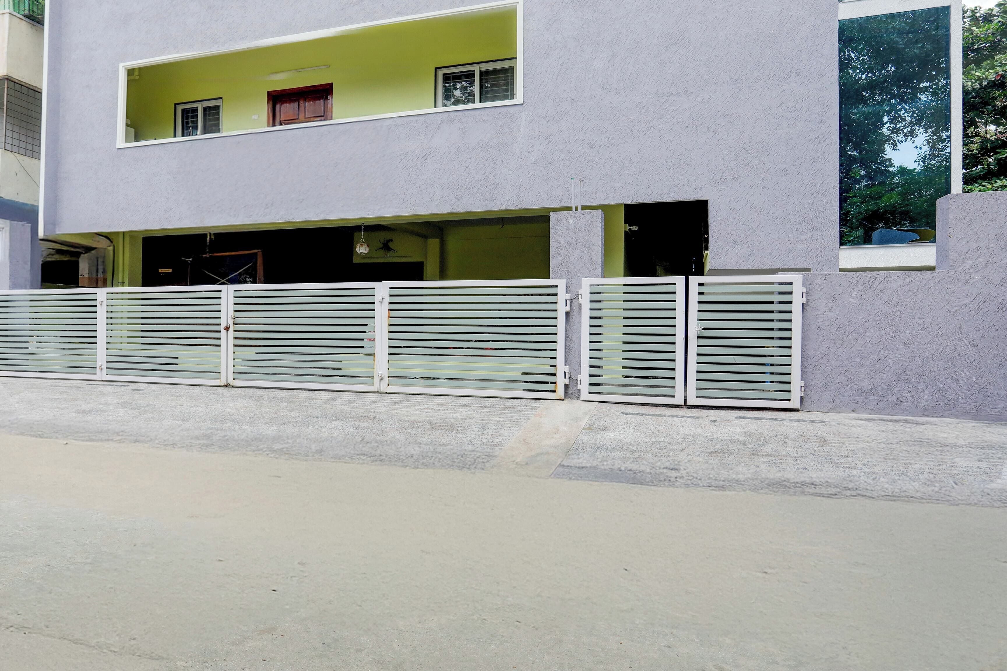 Un edificio de dos pisos con fachada plana, entrada protegida por una reja y puerta de garaje visible.