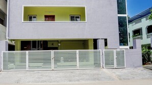A two-story building with a flat roof, a balcony on the upper floor, and a gated entrance. - Collection O Tirupati Railway (Tirupati)