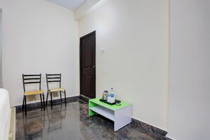 A hallway with two chairs, a door, and a small table with a kettle and water bottle.