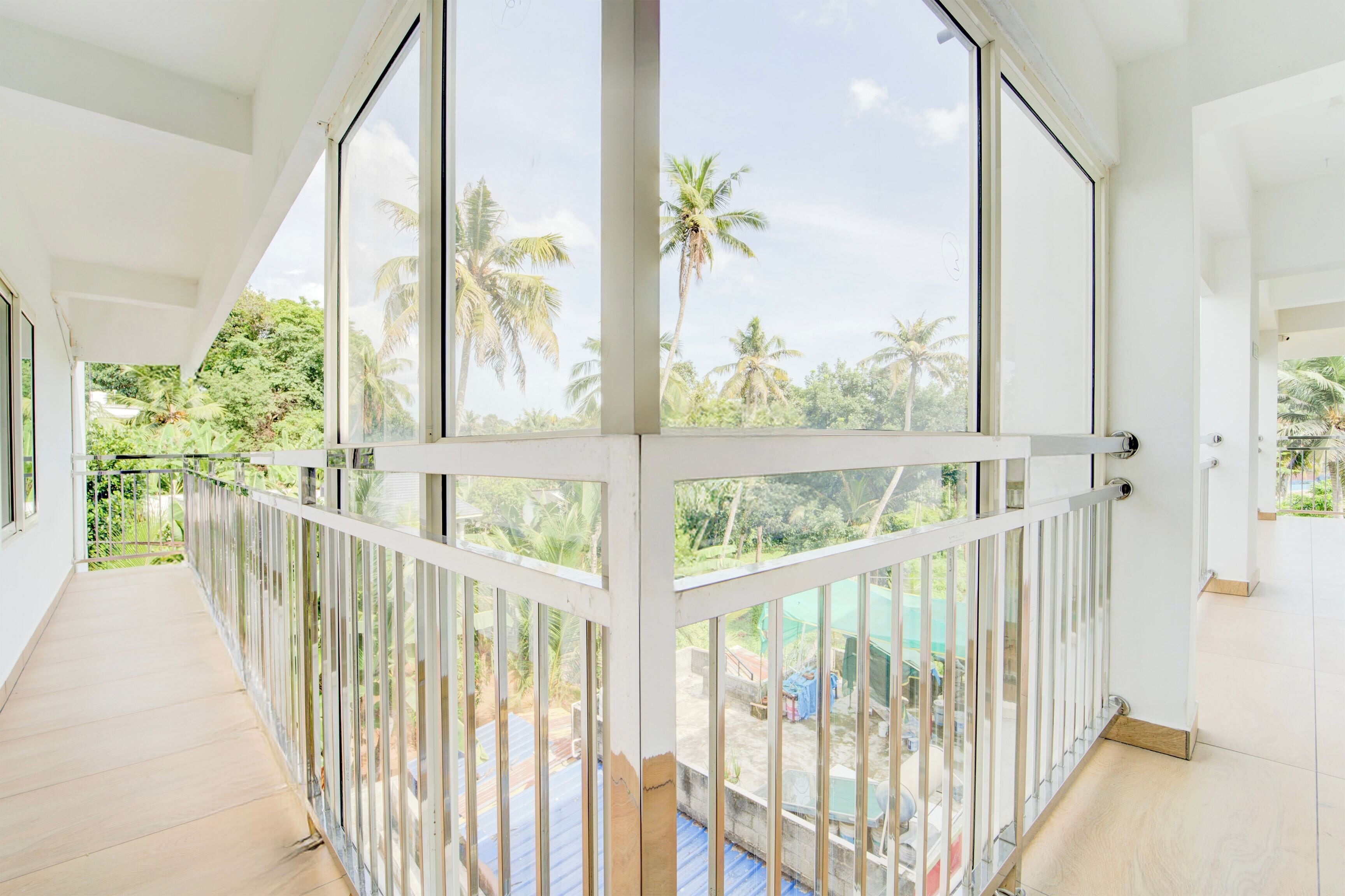 Un balcón amplio con vista a palmeras y una piscina.