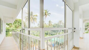 A spacious balcony with a view of palm trees and a swimming pool.