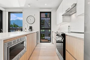 Eine moderne Küche mit Kochinsel, integriertem Backofen und Blick durch die Tür.