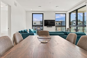 Ein modernes Wohnzimmer mit einem Holzesstisch, senfgelben Sofas und einem großen Fenster mit Bergblick.