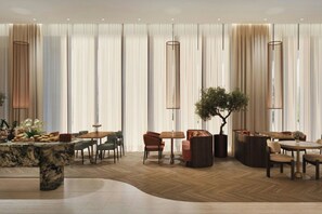 A spacious hotel lobby with a marble reception desk, multiple seating areas, and a large tree centerpiece. - AC Hotels by Marriott Airport City Belgrade (Belgrade)