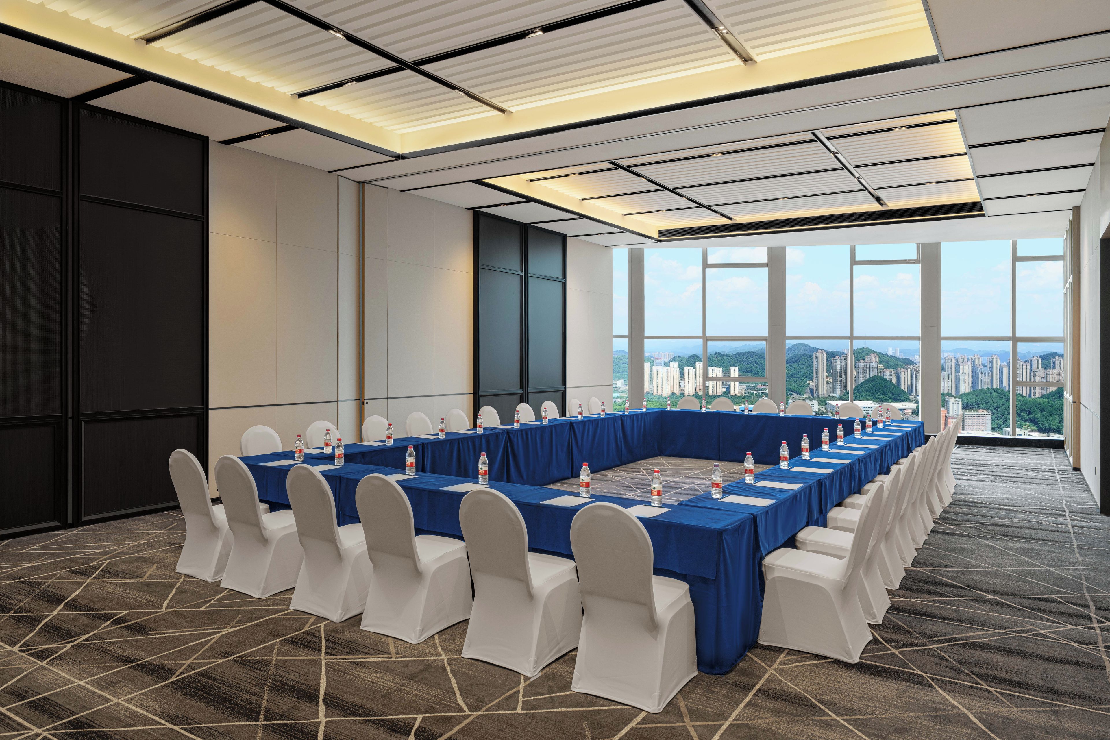 A conference room with a long table, white chairs, and a city view.
