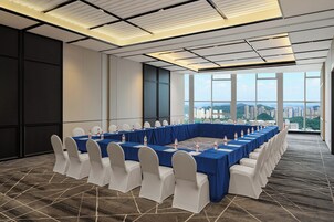 A conference room with a long table, white chairs, and a city view.