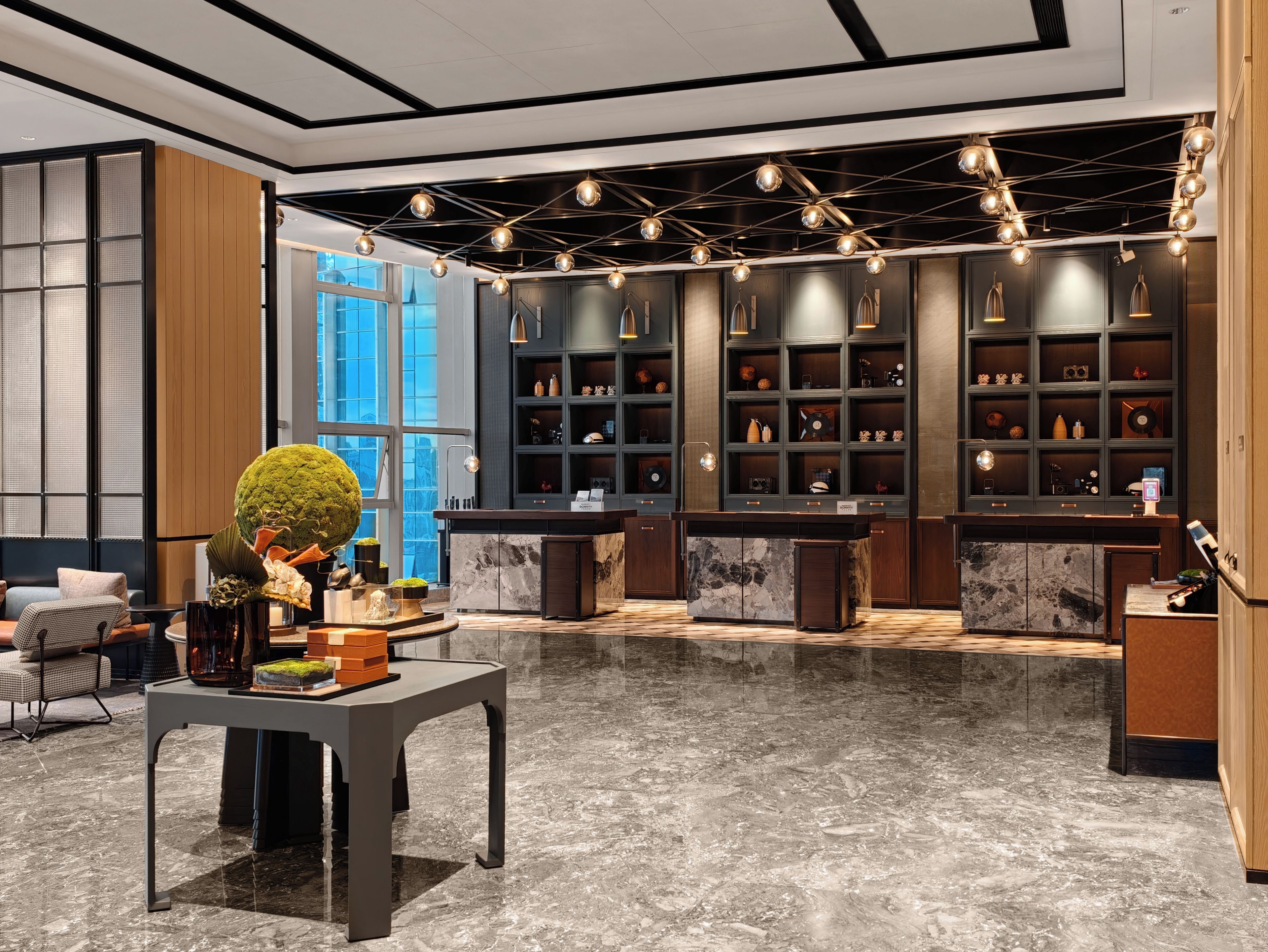 A modern interior with a marble floor, a reception desk, and a wall of shelves with various items.